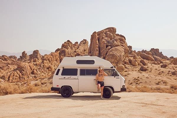 Christian & his VW T3 in the desert landscape of Alabama Hills, California - @christiandelatorre_ 09/2022 Christian de la Torre (@christiandelatorre_) leans against his white 1984 VW T3 Westfalia camper van in the rugged desert landscape of Alabama Hills, California. Surrounded by striking rock formations under a clear blue sky, the scene captures the essence of van life and the freedom of nomadic travel. The high-top camper van, central to Christian's van life adventures as described in his article, is parked in this iconic California destination, known for its connection to outdoor exploration and scenic beauty.