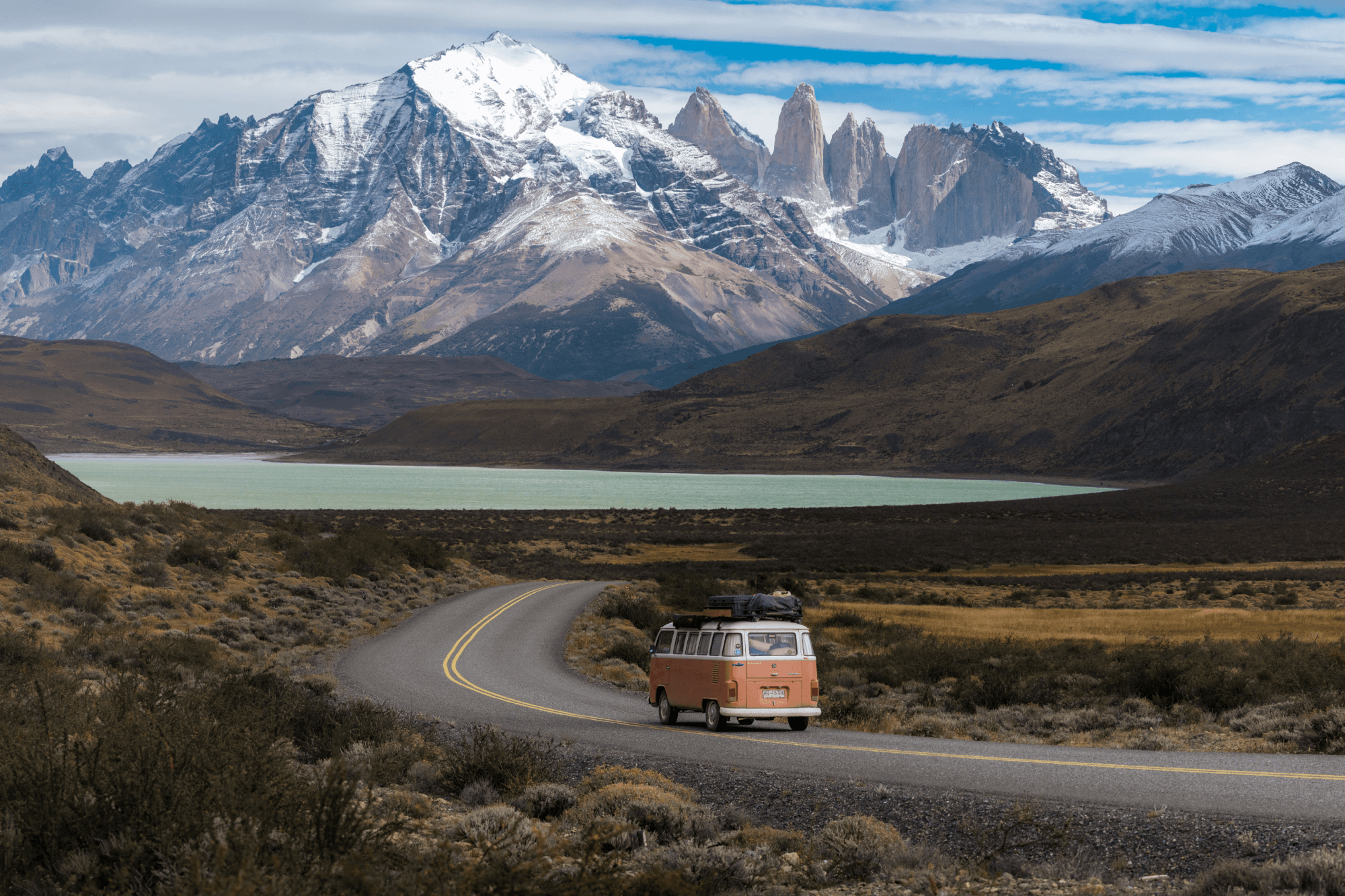 Exploring the Torres del Paine National Park - @octaviaviajando 09/2022 Victoria, the Chilean traveler behind @octaviaviajando, drives her vintage pink and white 1985 Volkswagen T2 Kombi along a winding road in Torres del Paine National Park. Towering snow-covered peaks and the iconic granite spires of the Cordillera Paine rise above a turquoise glacial lake in the background. This image captures the essence of her solo vanlife journey through Patagonia, blending adventure, nature, and sustainable travel in one of Chile’s most remote and breathtaking landscapes.
