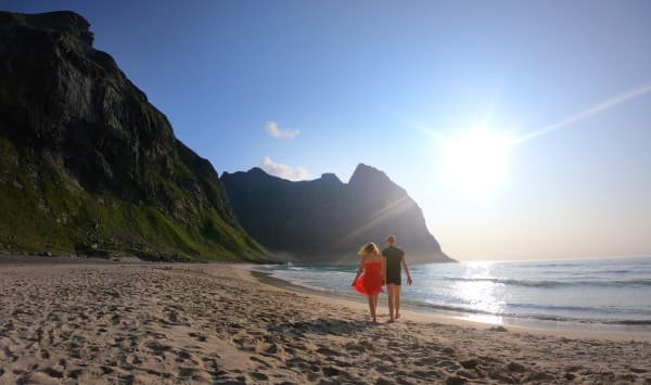 "The Caribbean of Europe" - @travelvan 08/2021 A couple, @travelvan, enjoying a serene walk on a sandy beach in Norway at sunset. The image captures the stunning contrast of the beach, the towering green mountains, and the calm ocean, highlighting the beauty of Norway's coastline.