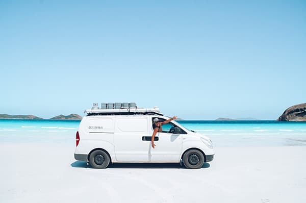 The white beaches of Esperance - @saltyvanlife 09/2022 The white self-converted van from @saltyvanlife parked on the pristine white sands of Esperance, Western Australia, with turquoise ocean waters and rocky islands in the background.